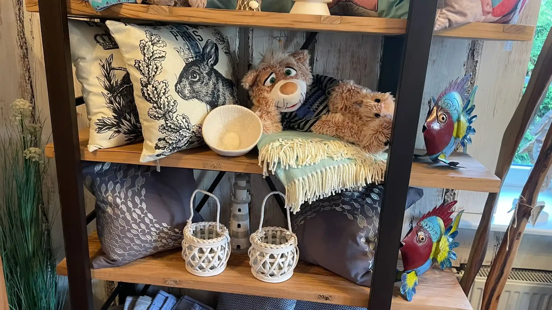 Deko-Regal mit bedruckten Kissen, Teddy, Laternen und bunten Metallfischen