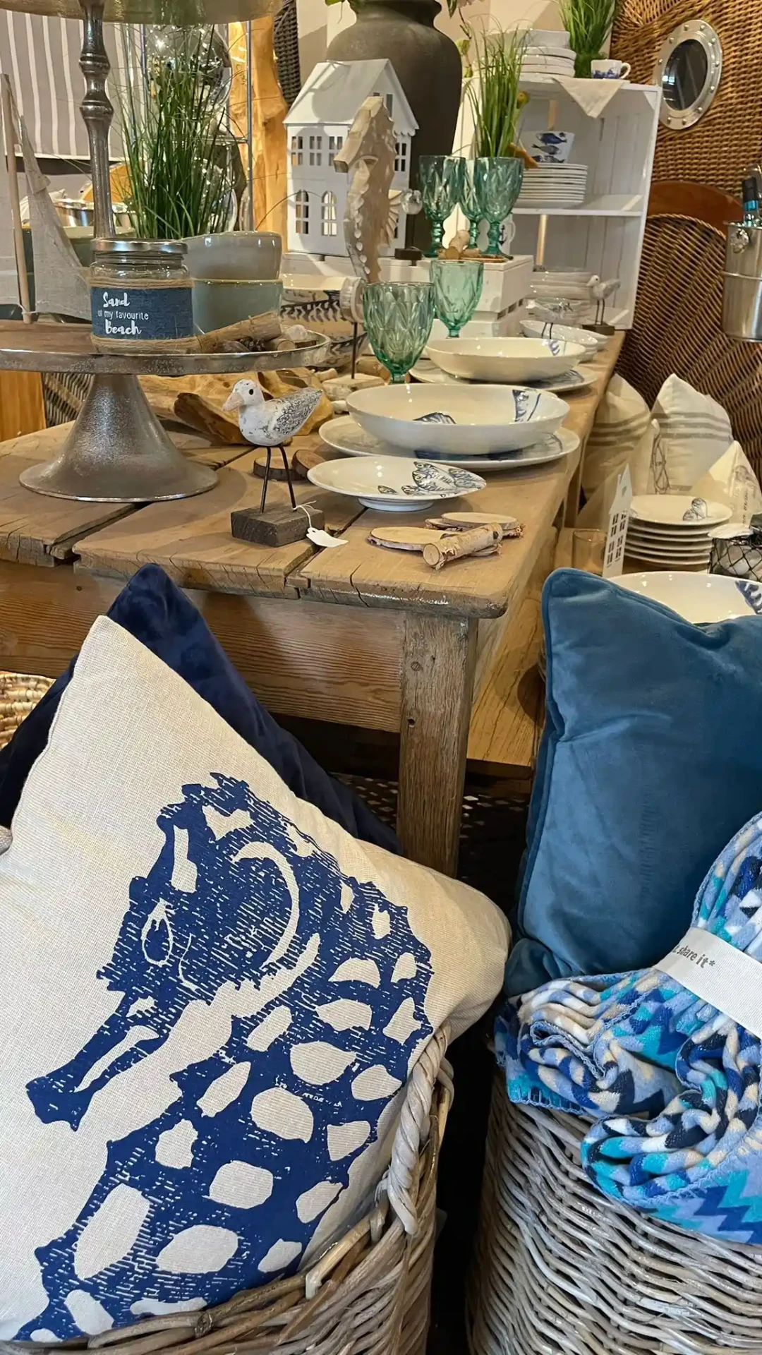 Maritime Kissen mit Seepferdchen-Motiv vor gedecktem Tisch mit Fischgeschirr