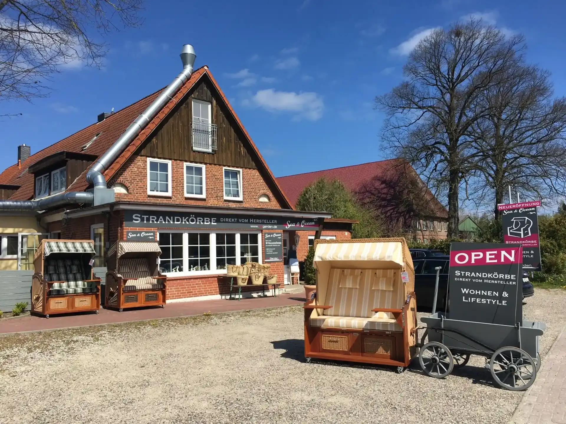 Sea & Ocean Laden in Hemmelsdorf — rotes Backsteingebäude mit Strandkörben, OPEN-Schild und blauem Himmel