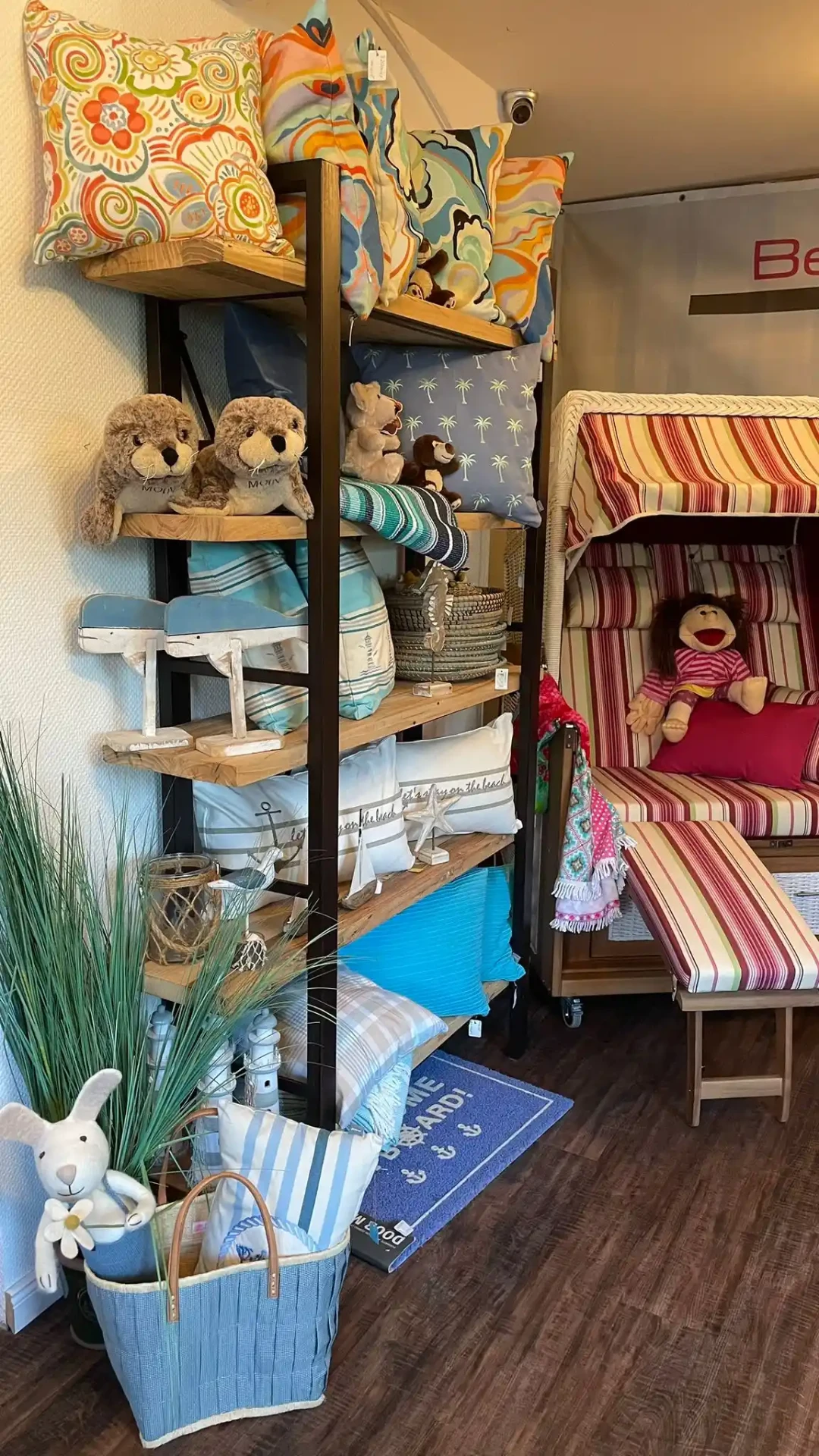 Rot gestreifter Strandkorb neben Regal mit maritimen Kissen und Kuscheltieren